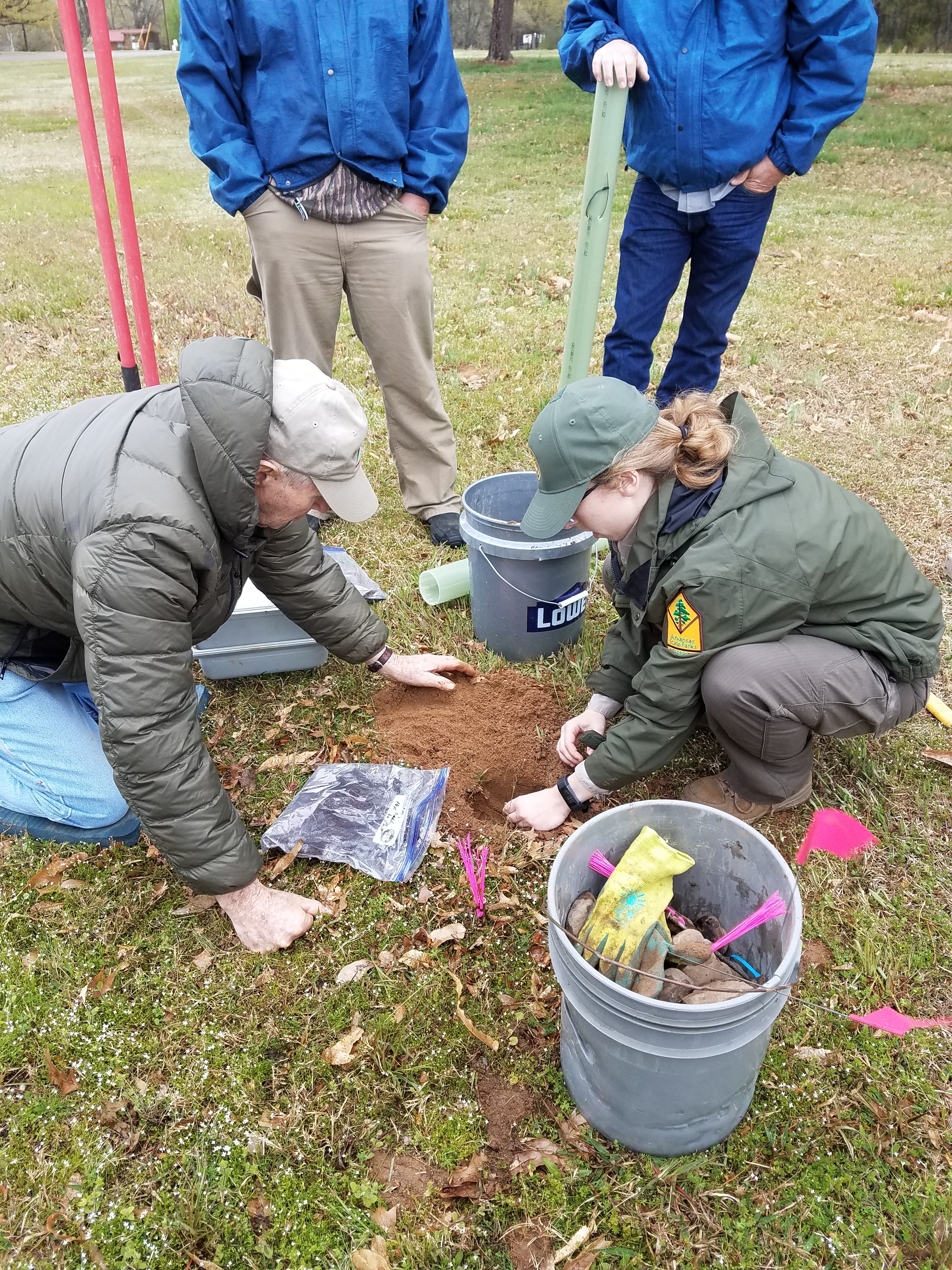 Park Interpreter Megan Ayres plants an Ozark chinquapin seed with the assistance of an OCF member at Lake Dardanelle State Park, while others observe. 